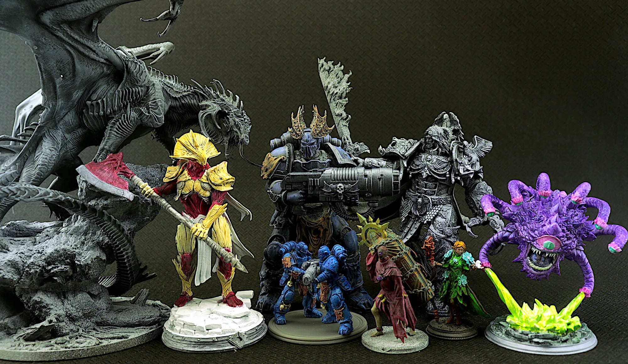 Collection of fantasy miniatures including a dragon, warrior, and various creatures on a dark background