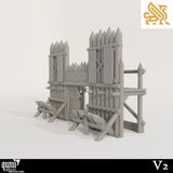 Front view of a wooden spiked wall terrain piece with a central gate and defensive barricades.