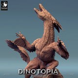 Side profile of the feathered Pyroraptor miniature standing on a rocky base with a fallen log.