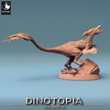 Side profile of a 32mm scale feathered Pyroraptor resin miniature standing on a rock base.