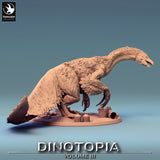 Top-down perspective of feathered Therizinosaurus miniature with saddle and items on floor.
