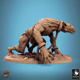 Side profile of a muscular, hunched troll miniature with chained wrists, standing on a rocky base.