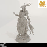 Side profile of a female druid miniature with tribal clothing, antlers, and a staff on a detailed base.