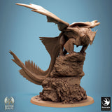 Bronze dragon miniature perched atop a craggy rock formation, detailed scales and wings visible