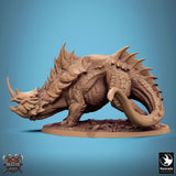 Side profile of a horned, armored reptilian beast miniature on a textured base against a blue background.